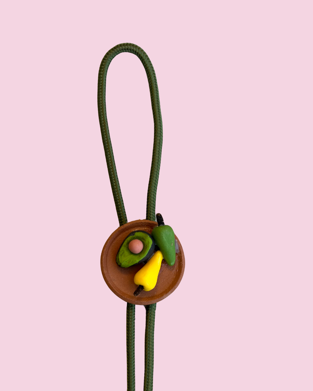 Avocado and chiles bolo tie pendant on pink background