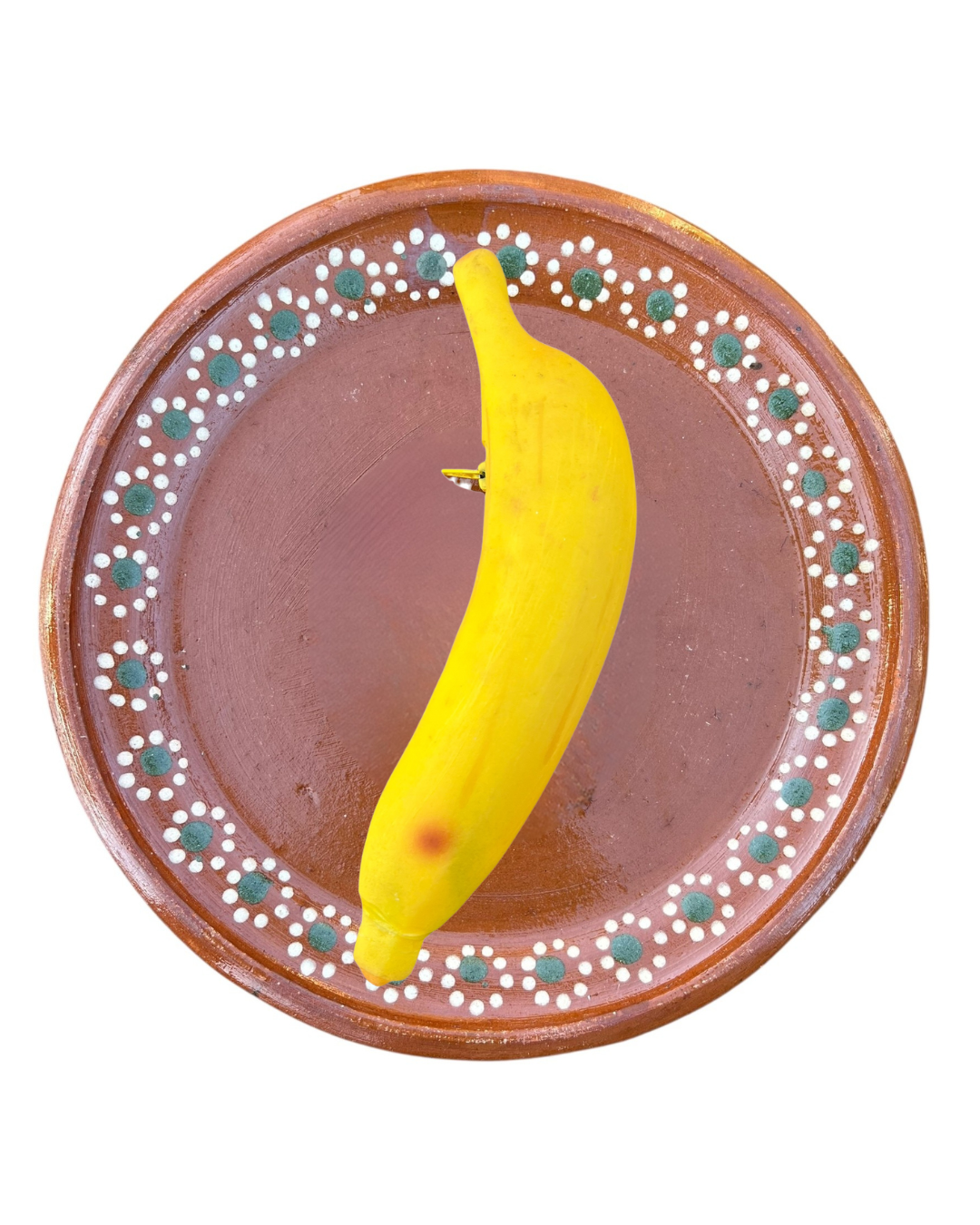 Yellow banana coin purse on a decorative brown plate with white and green patterns