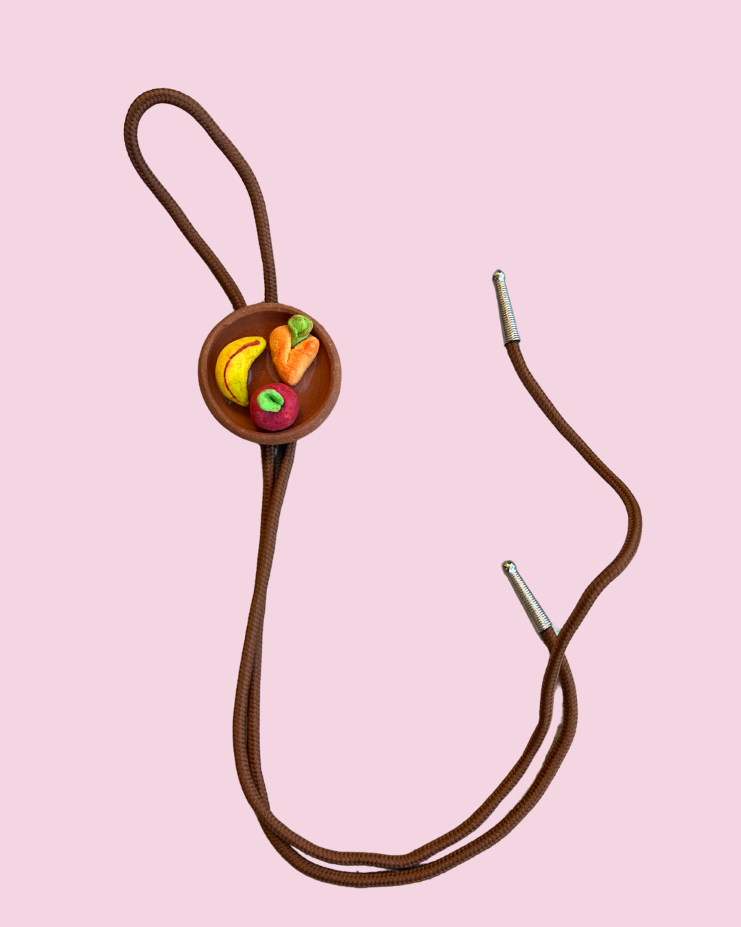 Plate of fruit bolo tie pendant on pink background