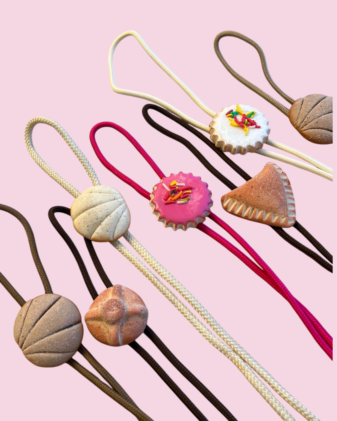 Decorative pan dulce bolo ties with unique designs on a pink background