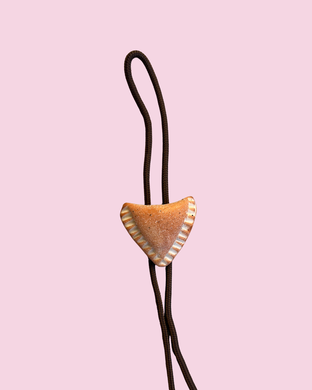 Bolo tie with a empanada pendant on a pink background