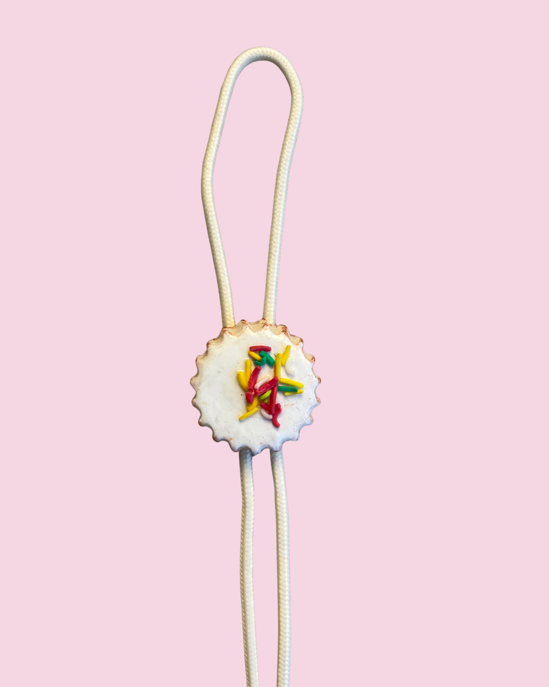 White cookie bolo tie on pink background
