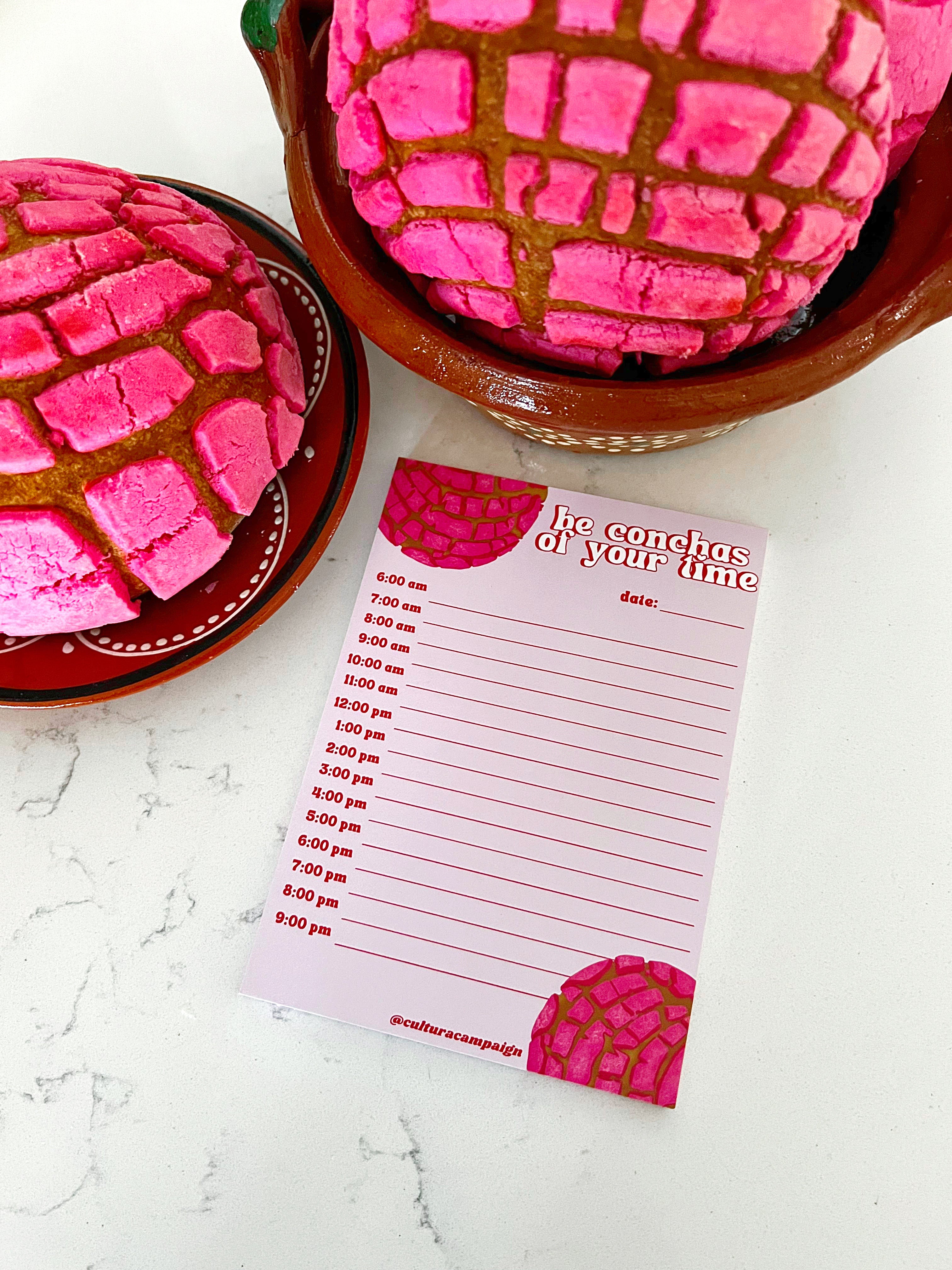 Notepad with a pink and brown design, featuring an illustration that resembles a traditional Mexican 'concha' pastry, with the text 'be conchas of your time" on the front.