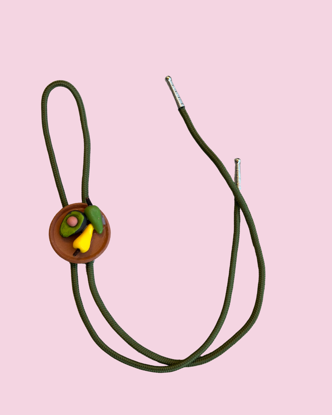 Avocado and chiles bolo tie pendant on pink background