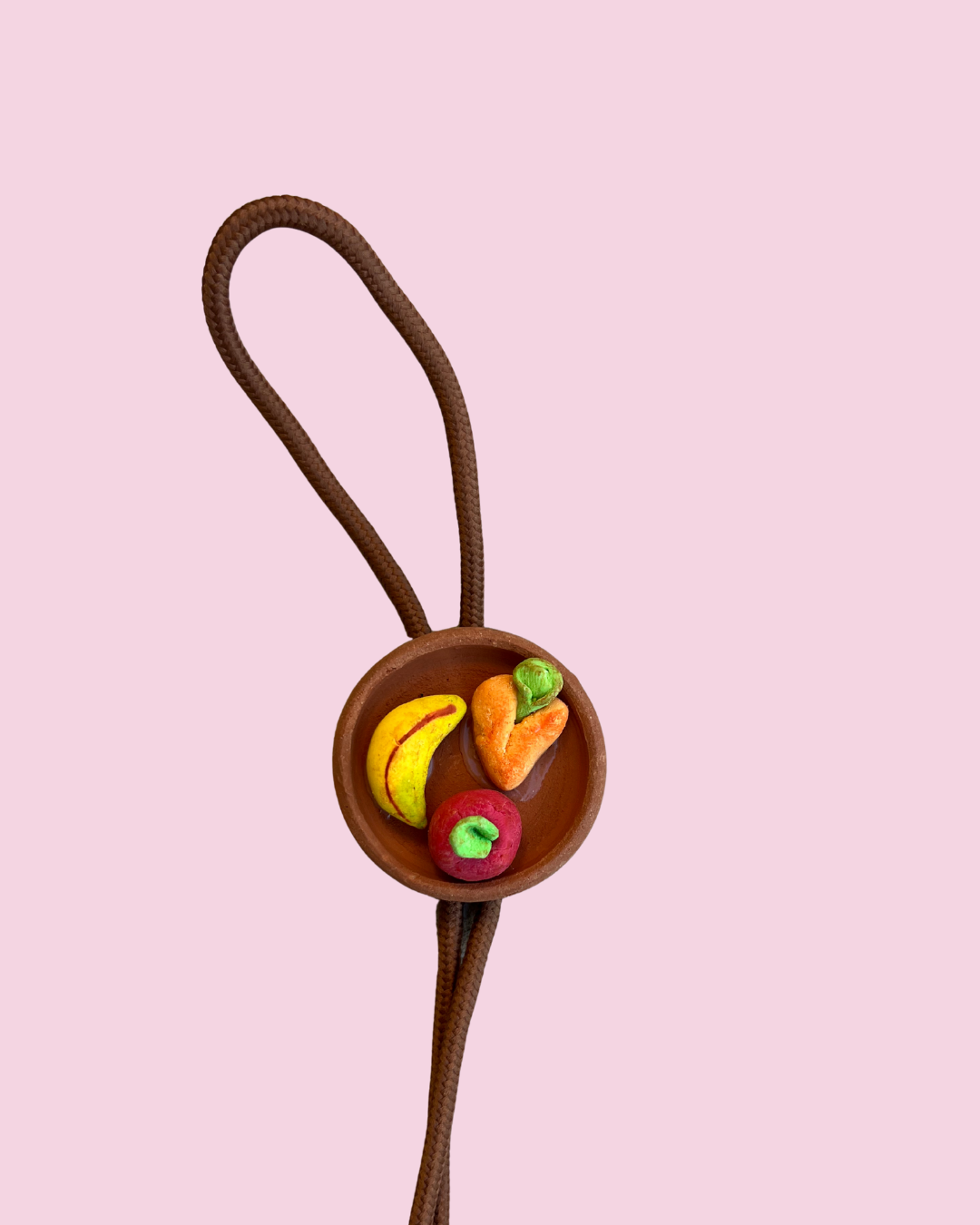 Plate of fruit bolo tie pendant on pink background