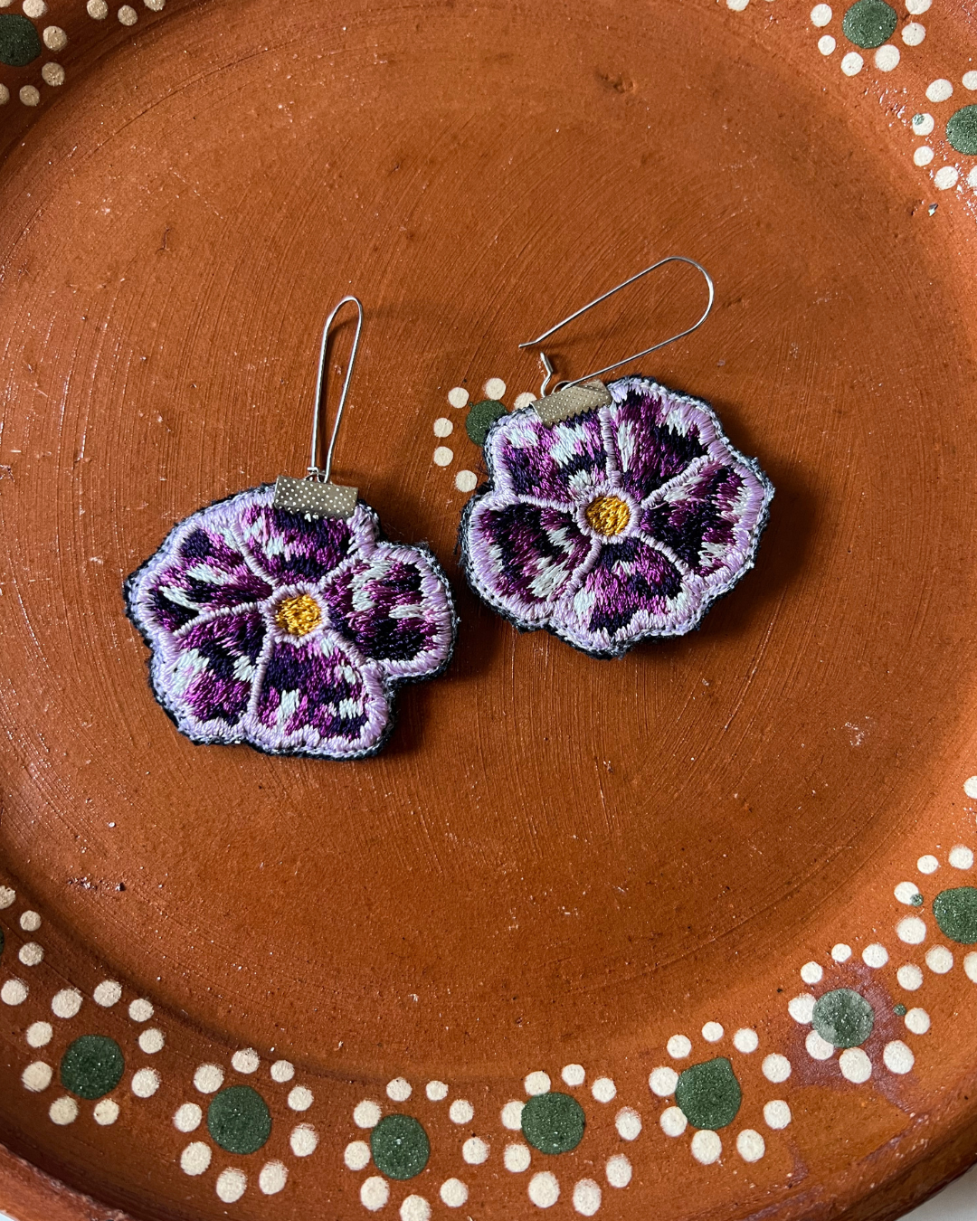 Embroidered flower earrings on a barro plate with floral patterns