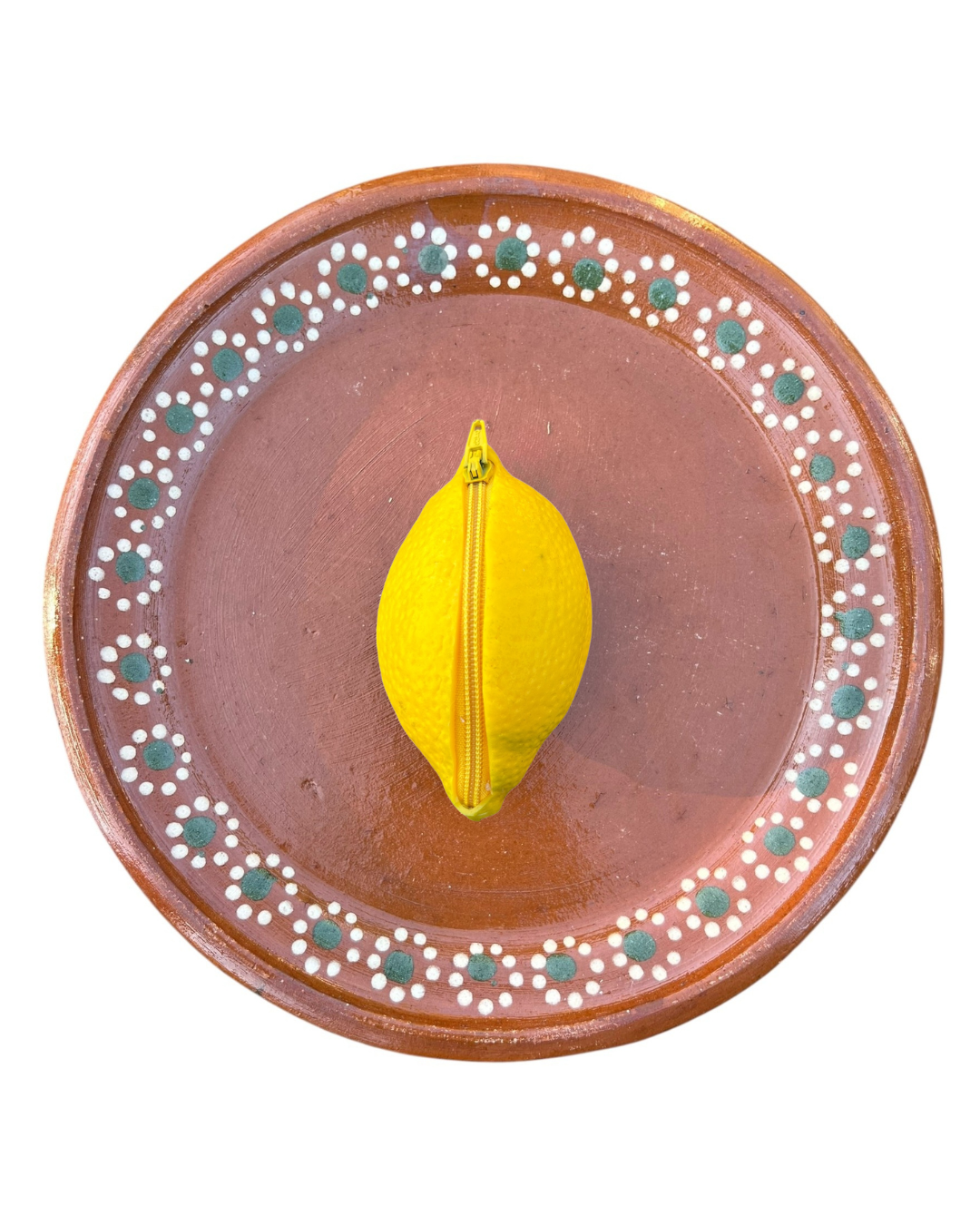 Ceramic plate with decorative edge and yellow lemon coin purse on a white background