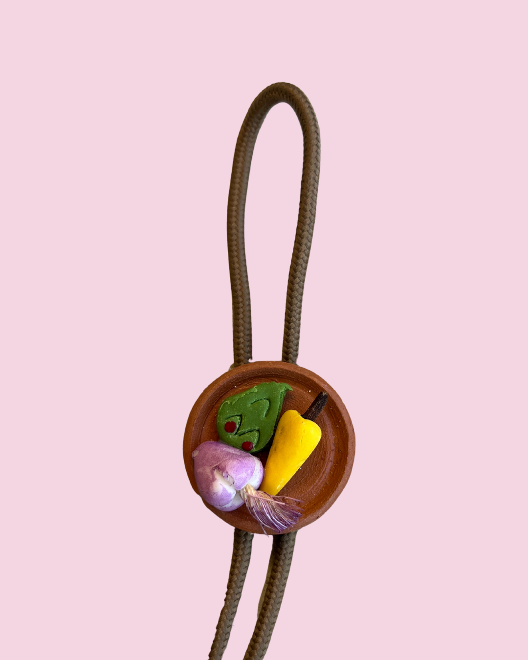 Bolo tie with plate of mexican food pendant on pink background
