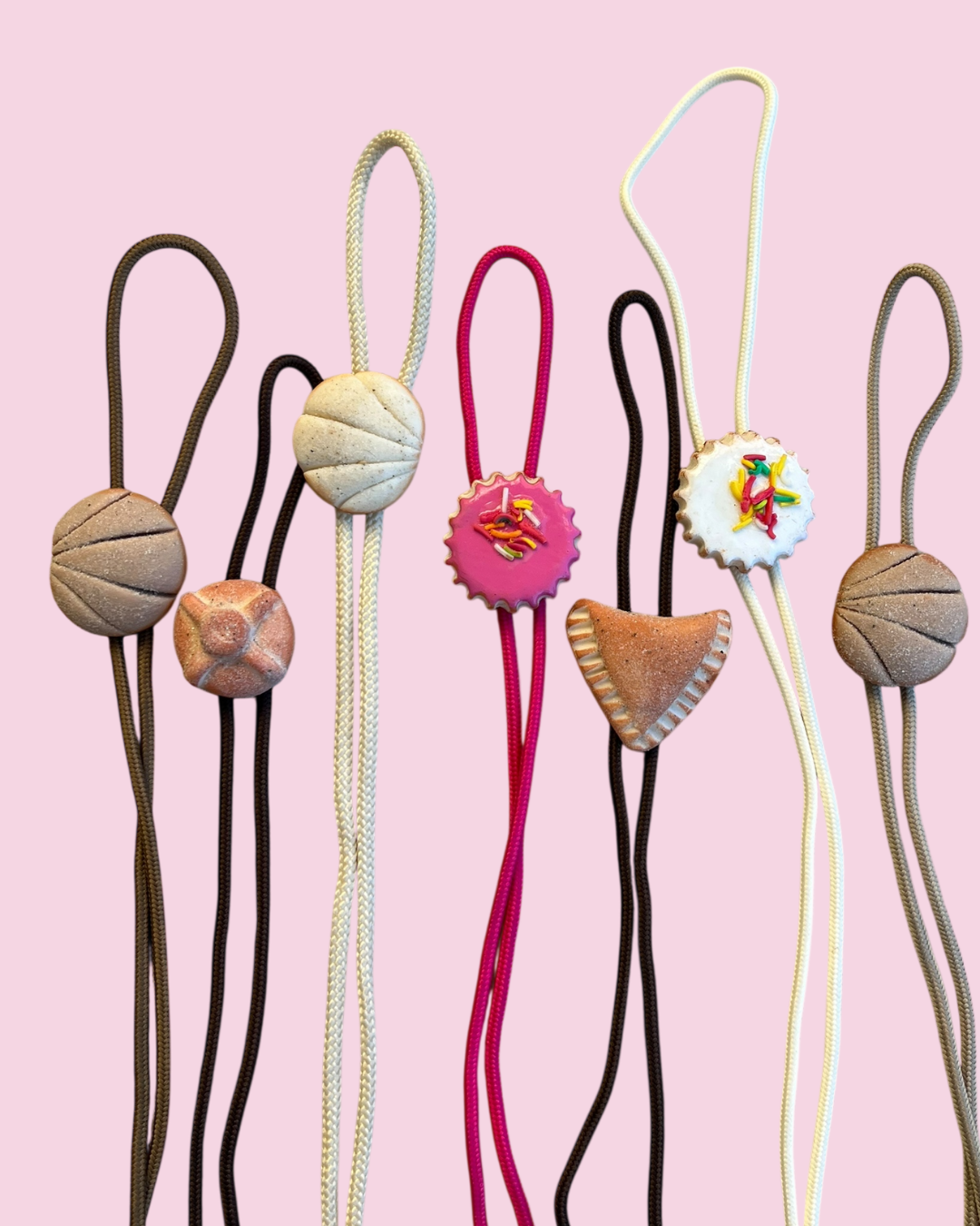 Colorful pan dulce bolo ties on pink background