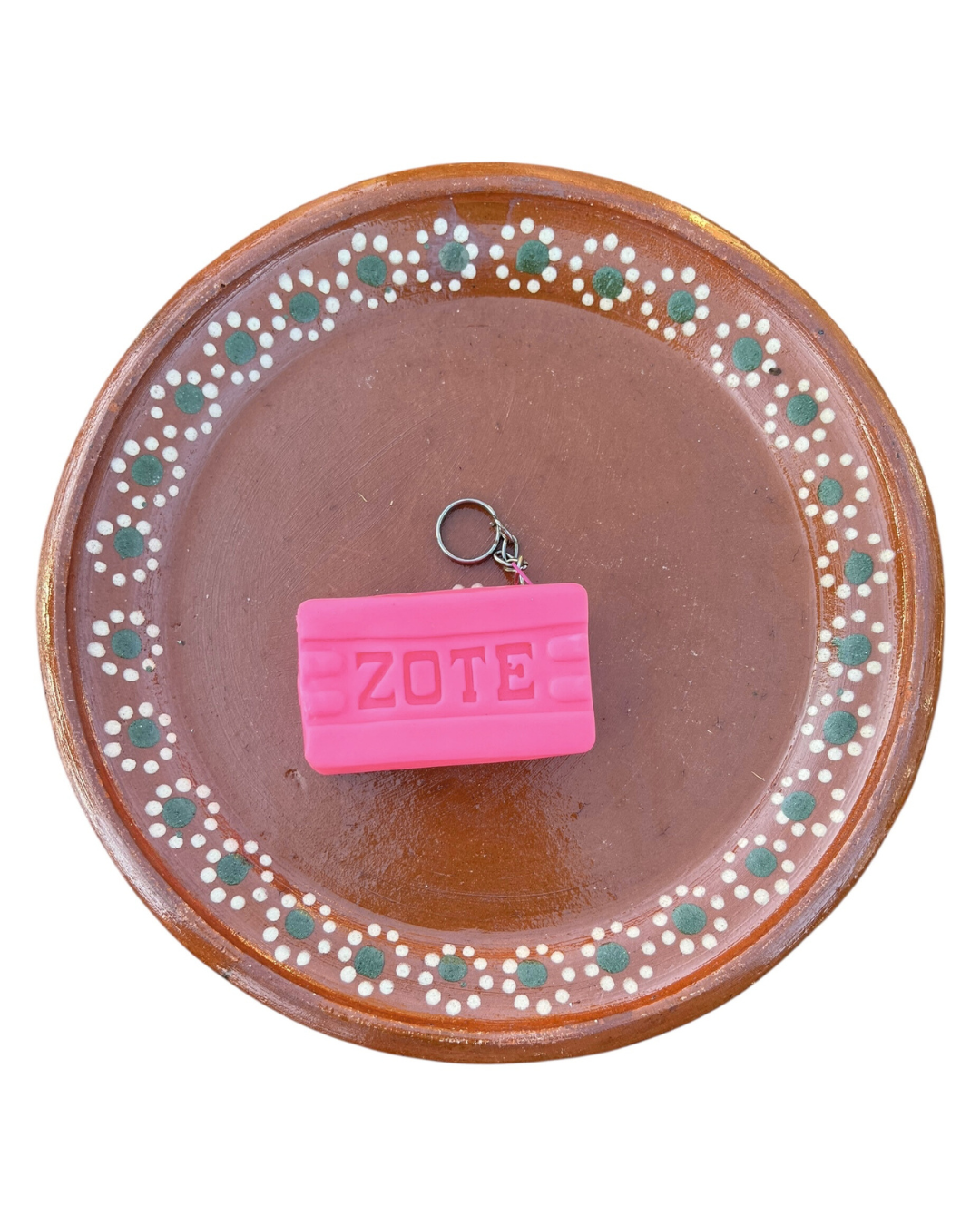 Pink 'Zote' coin purse on a decorative brown plate with white and green patterns
