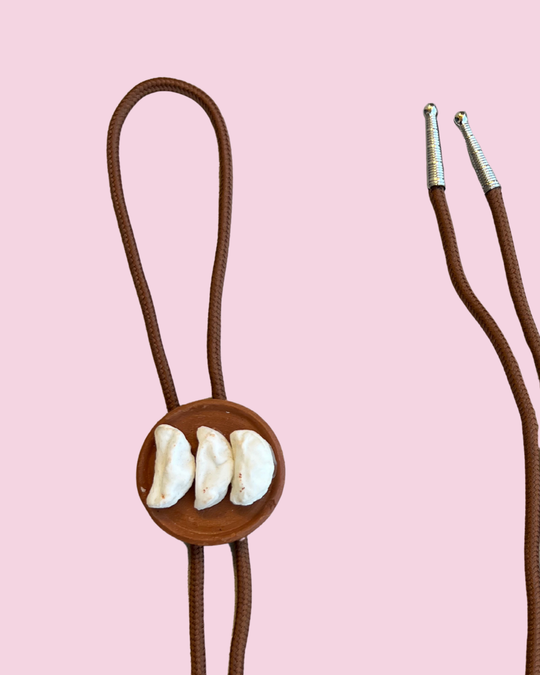 Bolo tie with three tortillas on a pink background