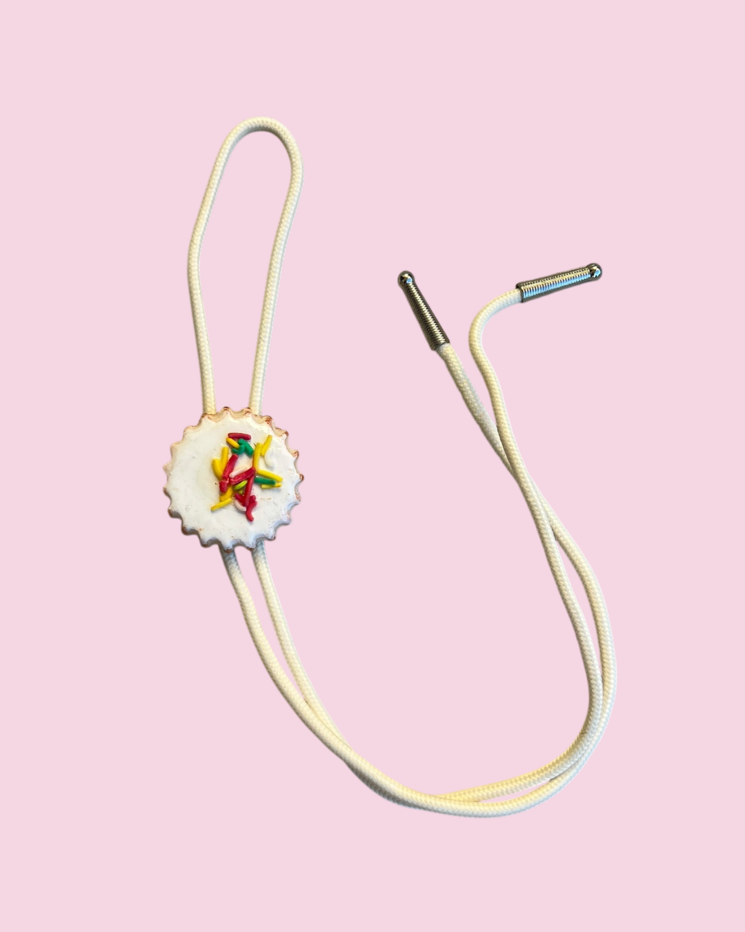Bolo tie with white cookie pendant on pink background