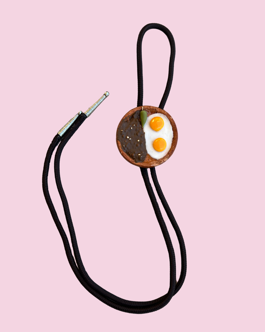 eggs and bean mexican plate bolo tie pendant on pink background